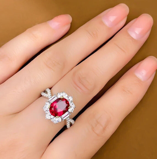 Woman's hand wearing an oval-cut red ruby engagement ring, showcasing its timeless elegance